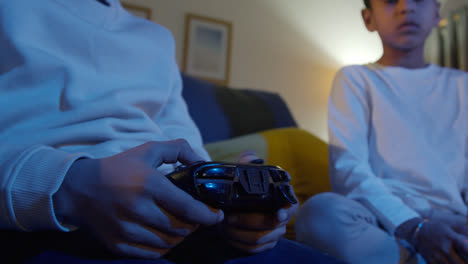 Close-Up-On-Hands-Of-Two-Young-Boys-At-Home-Playing-With-Computer-Games-Console-On-TV-Holding-Controllers-Late-At-Night-6